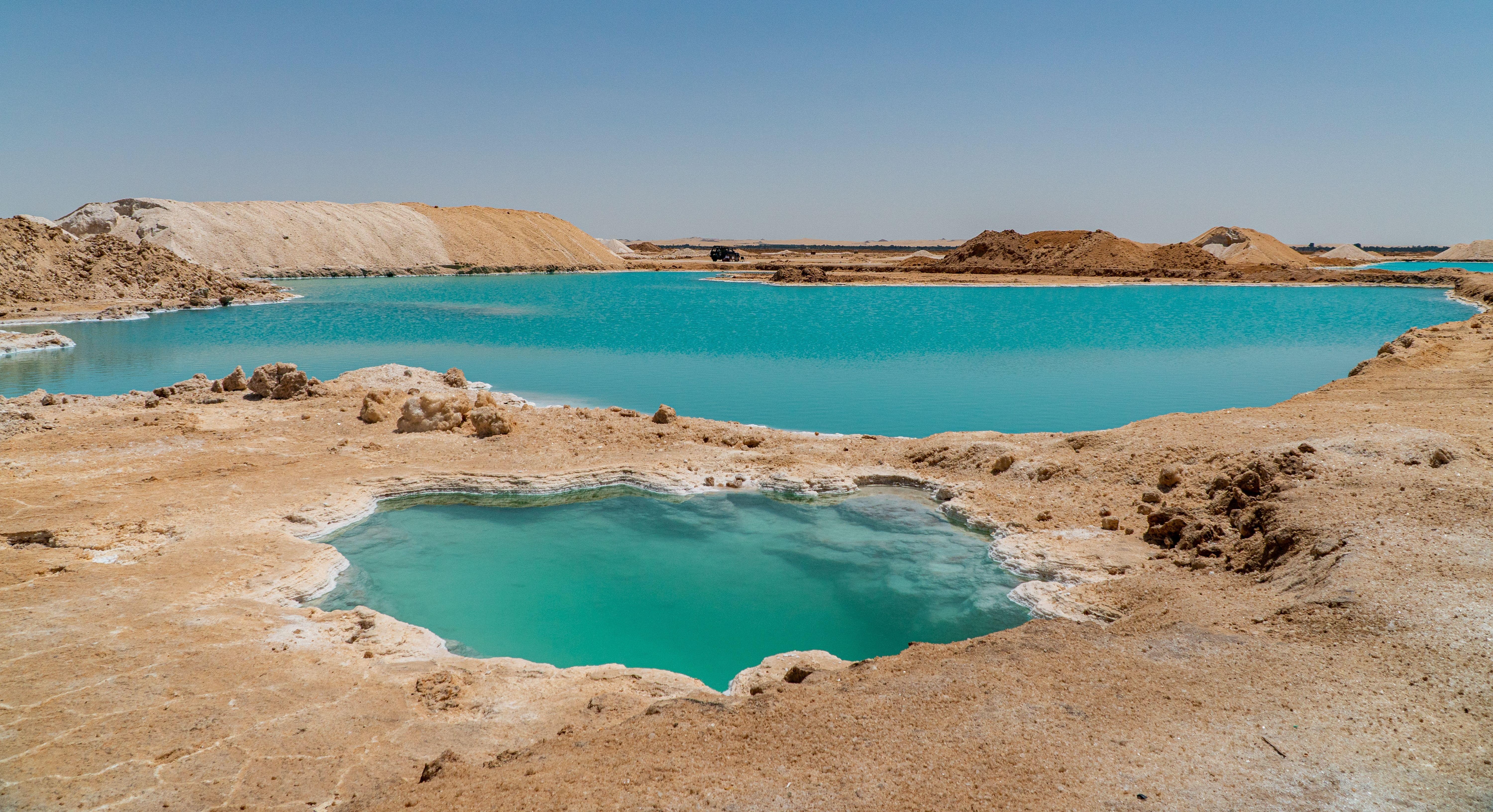 Multiple blue salt pools across the pale Siwa landscape